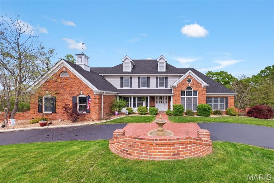 Welcome to this stunning 1.5 story custom home with circle drive, perfectly nestled on an acre lot in a private cul du sac overlooking the Meramec River Valley. Designed with character & charm, the quality craftsmanship of the home is evident with the use of gorgeous detailed millwork & rich materials. A grand two-story marble foyer sets the tone, opening into the custom wood-paneled, den with built-in shelving & palladium windows. The dramatic cathedral ceiling great room is impressive with gleaming, hardwood floors, a statement gas fireplace, and an expansive quartz wet bar with glass cabinetry, and complete with wine fridge. The chef’s kitchen is a gathering place, showcasing an abundance of shining quartz counters, a large center island with gas cooktop, and 42in. custom cabinetry, all leading into the sunlit, octagonal breakfast room or alternatively into the elegant formal dining room with coffered ceiling & bay window, ideal for entertaining large dinner parties. The main-level primary suite is a spacious retreat with glass french doors leading into the newly renovated, luxurious bath, featuring a spa-inspired soaking tub, dual vanities, custom walk-in closets, and vanity niche. The switchback staircase leads to the upper level featuring a charming loft with built-ins, a second primary suite, and additional bedrooms connected by a Jack-and-Jill bath. The walkout lower level enhances with a spacious family and recreation area with fireplace and direct access to the expansive outdoor patio with hot tub. The lower level also includes a workout room, full bath with steam shower, and a cedar closet, leading out to the 4th garage with rear entry and the expansive outdoor patio area complete with hot tub and firepit, perfect for entertaining guests or a game night with family. From the main level, step outside to a sprawling composite deck where both the breakfast room and great room open to gorgeous, private nature views—perfect for morning coffee or sunset gatherings. The features & updates are too numerous to list! Come experience it for yourself—this is more than a house, make it your next forever retreat.