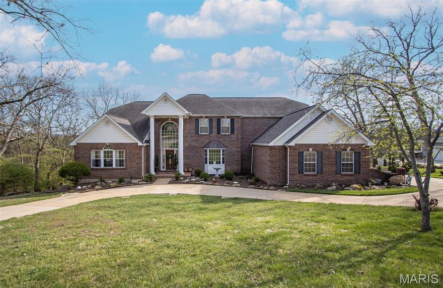 Situated on nearly 1.5 acres, this brick-on-three-sides custom home offers privacy, space, and craftsmanship not often found in today’s market. A 3-car garage, vaulted ceilings, custom millwork, and marble entry floors reflect thoughtful design and lasting quality. From the foyer, a grand staircase frames the entrance while a second staircase overlooks the Great Room—an impressive space with soaring 20+ ft ceilings, rich wood finishes, dramatic fireplace, and open railing above that creates a true sense of openness.

The granite kitchen flows seamlessly into a Hearth Room surrounded by a wall of windows, filling the home with natural light and connecting perfectly to the full bar—ideal for entertaining. A powder room off the foyer adds convenience, and the main-level Primary Suite provides a private retreat with direct access to a deck overlooking the backyard.

Upstairs, you’ll find two bedrooms and a versatile office (easily converted into a fifth bedroom if needed). One bedroom shares a Jack & Jill bath with the office, while the second enjoys its own private en-suite bath.

The finished walk-out lower level is built for both everyday living and entertaining, offering two separate living areas, two fireplaces, a full bar, and space for a pool table, along with a large bedroom and bath that’s perfect for guests or extended family.

Recent updates include a new roof (2025), Great Room windows (2024), and a refinished deck (2023). With tall ceilings, open sightlines, multiple gathering spaces, and a private lot just behind Mercy South and minutes from shopping and dining, this home blends character, natural light, and entertaining potential in a one-of-a-kind setting.