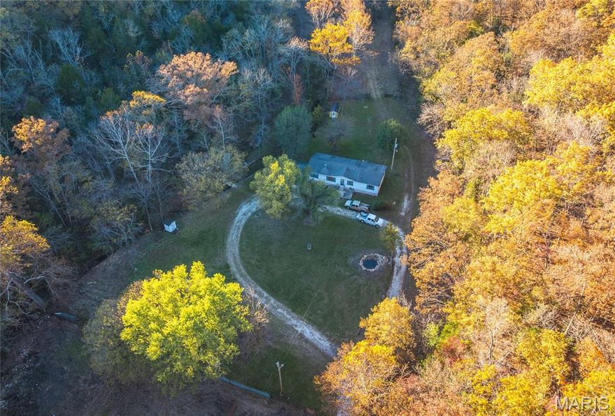 Discover this stunning 11+ acre retreat nestled in the picturesque Ozark Hills. This truly unique property features cleared pastureland, some enclosed with sturdy pipe fencing, ideal for grazing or farming, and some wooded land perfect for outdoor exploration. A spring-fed creek meanders through the property, providing natural water for livestock in the front pastures, while a historic artesian well and old-time well house—once used for milk storage—add charm and character.

A quaint wooden bridge spans the creek, leading to a beautifully crafted pavilion carved into the hillside, offering a serene spot to relax and enjoy nature. In the front yard discover a custom waterfall fountain and a charming koi pond, enhancing the tranquil setting. 

The existing mobile home features an open floor plan with ample space, a large living room with a fireplace, and a spacious primary suite with a walk-in closet, private bathroom with a jetted tub, double vanity, and separate shower. The home offers flexible use; with a little updating, it can serve as the primary residence or serve as temporary housing while you build your dream home. This home also comes with a 24x24 two-car garage and two additional storage sheds.

This land truly embodies the beauty of the Ozarks—spring-fed waters, mature trees, surrounded by woods, lush pastures, and peaceful outdoor living. A premier piece of Ozark real estate, perfect for those seeking privacy, nature, and potential. Additional 47 acres +/- available see mls listing 25071103.