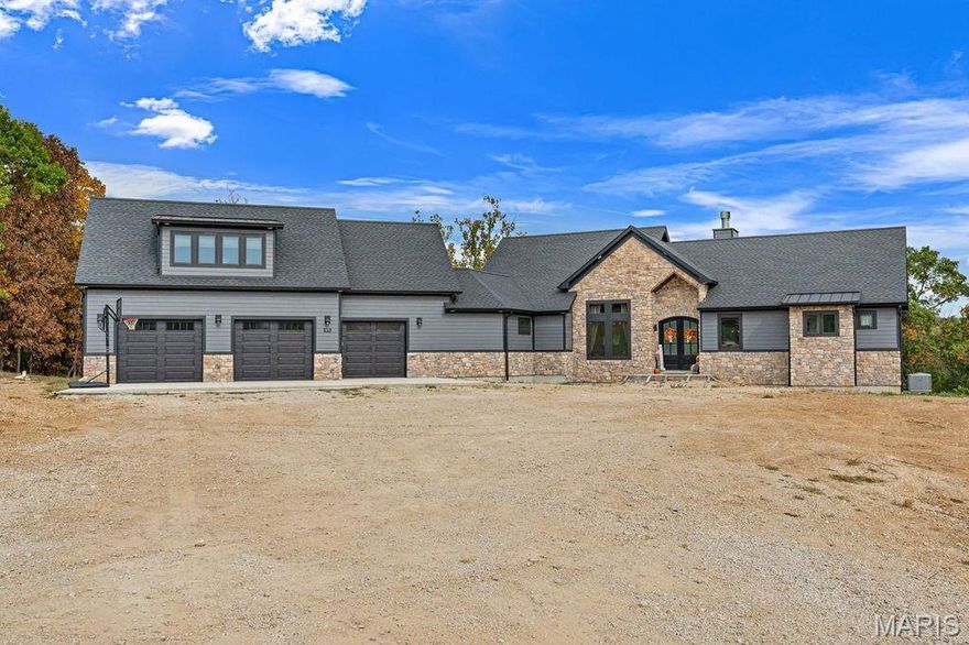 A true Masterpiece in Hidden Ridge! Nestled on 7.85 acres of rolling countryside just east of Washington, Missouri, this jaw-dropping custom-built 1.5-story home offers over 2,700 square feet of thoughtfully designed living space where craftsmanship, comfort, and natural beauty meet in perfect harmony. From the moment you arrive, the home’s commanding presence and stunning stone-and-wood exterior set the tone for what lies within. Inside, a warm yet sophisticated atmosphere unfolds—anchored by a striking floor-to-ceiling stone fireplace and enriched with custom finishes at every turn. The open-concept kitchen is a showpiece, featuring custom-painted cabinetry, an oversized island perfect for gathering, tile backsplash, solid surface tops, and a generous walk-in pantry. The great room soars with tongue-and-groove vaulted ceilings, flooding the space with light and accentuating the home’s spacious flow. The main-floor primary suite offers a serene retreat with its own vaulted ceiling, dual walk-in closets, and a luxurious ensuite bath complete with a double vanity and expansive walk-in shower. A dedicated office area provides an ideal space for working from home or creative pursuits. Upstairs, the bonus area above the garage offers incredible versatility with a family room, two additional bedrooms, a full bath, and even a laundry space—ideal for guests, older children, or extended stays. Every room has been designed to capture the breathtaking views that surround the property, creating a seamless connection between the indoors and nature’s beauty beyond. The oversized 3-car garage provides a true zero-step entry into the home for ease and accessibility. For those who dream of extra space to entertain, create, or store, the impressive 45’x140’ detached garage opens endless possibilities—from car collections to workshops, gatherings, or future expansion. This exceptional property combines the allure of modern luxury with the tranquility of a private, countryside setting. Whether enjoying a quiet evening by the fireplace, hosting gatherings under the vaulted ceilings, or taking in panoramic sunsets from your own backyard, every moment here feels extraordinary. A rare opportunity to own a custom estate of this caliber in the Hidden Ridge community—where craftsmanship meets breathtaking views and peaceful living.