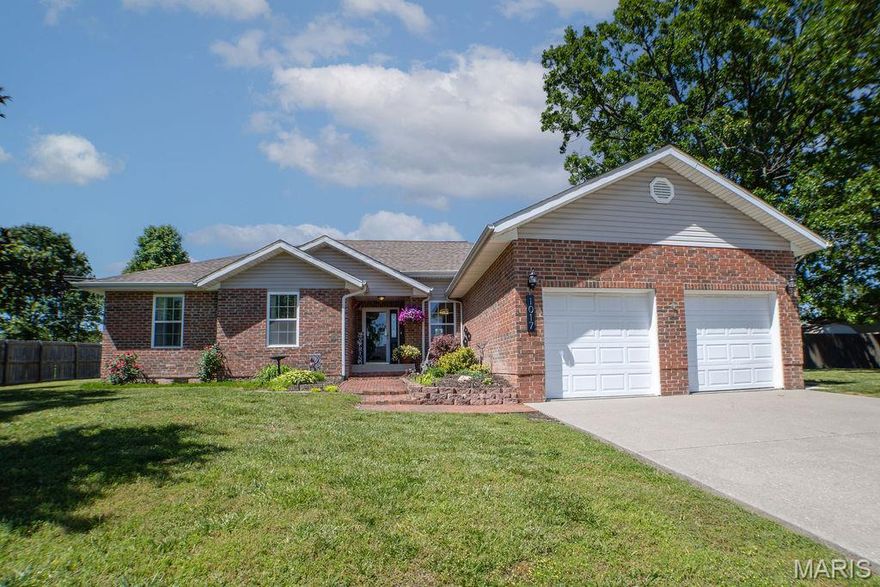 Welcome home to this warm and inviting 4 bedroom, 3 full bathroom home in Lebanon offering nearly 2,000 square feet of comfortable living space, thoughtful updates, and plenty of room to make memories for years to come. From cozy movie nights in front of the fireplace to summertime cookouts in the backyard, this home was made for gathering with the people you love the most.
The brick and vinyl exterior offers timeless curb appeal along with low-maintenance living, while the newer roof gives added peace of mind. The lush landscaping, mature trees and manicured lawn are gorgeous and something you can be proud of. Stepping inside from the covered front porch to the formal entryway, you’ll find durable LVP flooring flowing through much of the home, creating a warm and updated feel that’s both stylish and practical for everyday life. The spacious living room features a stone fireplace, making it the perfect place to curl up on chilly evenings or enjoy lazy weekend mornings with coffee in hand. One of the best and most unique features of this home is that there are TWO primary suites, giving flexibility for guests, multi-generational living, or just simply providing extra privacy. The larger primary suite feels like its own private retreat with a cozy fireplace, sitting area, walk-in closet, jetted tub, and walk-in shower—perfect for winding down after a long day. The remaining 2 guest rooms are good sized, both offering tons of natural light, and the guest bathroom is centrally located close to both of them. The kitchen offers custom cabinetry, stainless steel appliances, a breakfast nook and breakfast bar for casual meals, and a pantry to help keep everything organized. Just off the front entryway, the formal dining room is ready for holiday dinners, birthday celebrations, and all the little moments in between. A dedicated laundry room adds even more convenience to everyday living. Stepping outside and into the backyard and you can easily imagine evenings spent grilling on the back deck while kids or pets play in the yard. Need extra storage or workspace? The large workshop/storage shed with electric and an overhead door is ideal for hobbies, projects, tools, or recreational equipment. Plus, the attached 2-car garage gives you even more room for vehicles and storage. Homes like this have a way of feeling comfortable the moment you walk through the door—and this one is ready for its next chapter. Call to schedule YOUR personal tour TODAY before this beautiful home is gone!