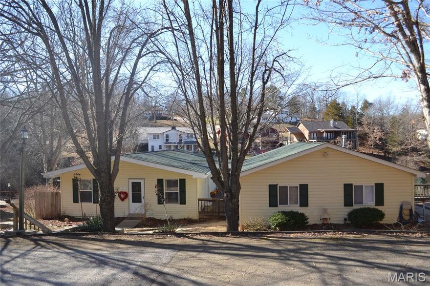 Step into this charming lakeside home that boasts 3 bedrooms and 2 full baths! Sitting on a double lot right on Lake Carmel, you can enjoy the view from the large wooden deck wrapping around the house, the screened-in patio downstairs, the swimming pool, or the boat house! This home has been maintained very well and a new roof was installed within the past 3 years. A large, detached 2-car garage is connected to the home by the deck. The updated kitchen and open living/dining space, complete with new wood flooring, are on the main floor, as well as the primary bedroom. There are 2 bedrooms downstairs, one of which could be converted into an In-Laws Suite. The downstairs family room features a fireplace and a walk-out to the patio. From there, you can walk down to the boat house to enjoy the peaceful lake life and community of Terre Du Lac!