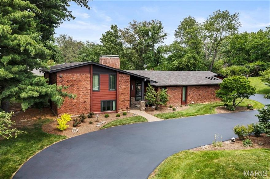Nestled in the Ladue School District, this 4-bedroom, 3.5-bath home welcomes you with a foyer featuring a soaring rock wall & globe lights. An adjacent mini-bar and conversation pit with a fireplace set against a 14-foot rock accent wall add flair. The entry flows into an open-concept layout that seamlessly connects the great room, dining area & kitchen. The vaulted great room showcases the rock-wall design and includes a built-in 60-bottle wine rack with large windows filling the space with light. The kitchen includes white custom cabinetry, granite countertops, a center island and stainless-steel double ovens with a matching Sub-Zero refrigerator and freezer. The three-season room extends living space from spring through fall, with a commercial barbecue grill on a brick base, copper exhaust hood, and ceiling fans for al-fresco gatherings. On the upper level, the primary suite has a remodeled master bathroom with a Jacuzzi tub, glass-enclosed shower and elegant finishes. The second bedroom also has an ensuite bath. On the lower level, two bedrooms share a full bath and a family room opens to the backyard. A partially finished basement offers a recreation area for games, media, or relaxing. A circular driveway leads to a three-car garage. The backyard boasts a 22' x 42' inground pool, 12' deep with a diving board, and stamped concrete decking. Outdoor amenities include a putting green, a basketball goal, and a spacious side yard framed by landscaping.