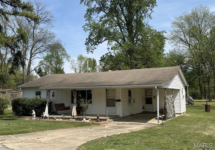 Charming and solid two-bedroom home on a corner lot with one full bath. The 1,014 sq. ft. layout features a living room, dining room, and kitchen with gas range, disposal, and dishwasher. Step through the nearly new patio door to a covered deck and fenced yard, great for pets or play. A storage building holds tools and lawn equipment. Inside, hardwood floors and roomy closets enhance both bedrooms. Comfort is provided by a natural gas wall furnace and two window A/C units. The hall bath offers a tub/shower and updated vanity. Additional highlights include a composition shingle roof, gutters, vinyl siding, covered front porch, and a concrete driveway leading to a carport—combining comfort, convenience, and classic appeal.