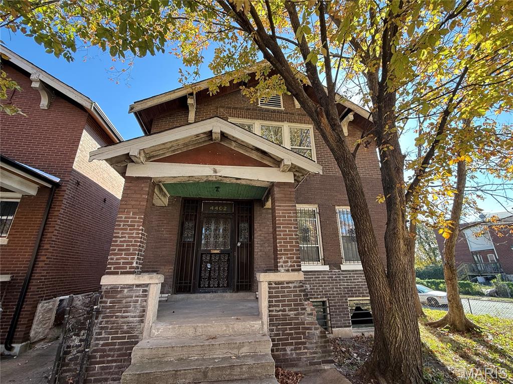 View of exterior entry featuring brick siding and a porch