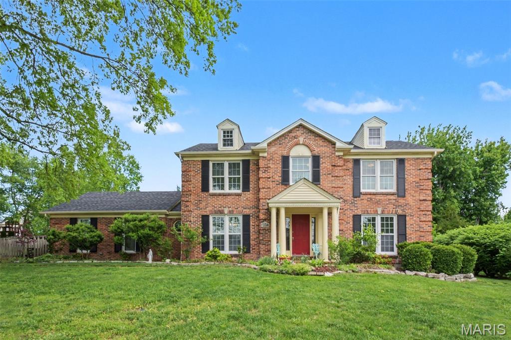 Brick exterior with multiple gabled dormers and black louvered shutters
