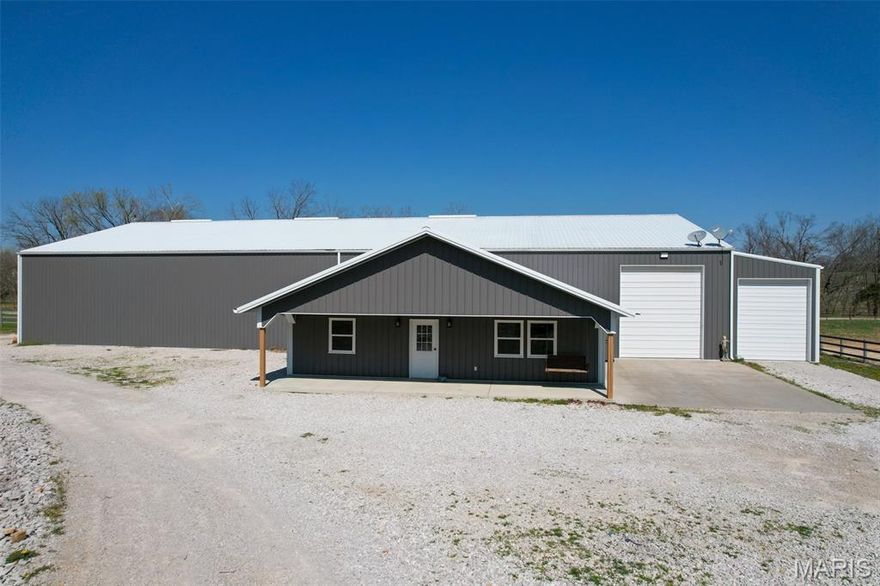 This property features a well-maintained and recently constructed building designed to support a variety of uses, including residential living, equine operations, and hobby or workshop activities. Built in 2020, the 7,350 square foot structure offers a combination of finished living space and functional agricultural improvements. The living quarters encompass approximately 1,650 square feet and include three bedrooms and two full bathrooms. The layout provides a full kitchen equipped with appliances, a dedicated living room area, and integrated laundry with a washer and dryer included. The interior is designed for practical, everyday use with durable finishes and efficient use of space. Attached to the main structure is a 60 x 80 horse barn equipped with 14 stalls, offering infrastructure for equine housing and management. The barn layout allows for organized stall arrangement and ease of access for feeding, cleaning, and general care. This setup supports a range of uses from personal horse ownership to small-scale boarding or training operations. The property also includes both indoor and outdoor riding arenas, providing space for year-round training, exercise, and riding activities. The indoor arena offers a covered environment for use in various weather conditions, while the outdoor arena allows for additional riding space and flexibility. In addition to the barn and arenas, the property includes a 30 x 60 shop with a concrete floor. This space is suitable for equipment storage, maintenance, woodworking, or other mechanical or hobby-related activities. The size and construction of the shop provide flexibility for a variety of operational needs. The exterior features include a covered front porch, providing a sheltered outdoor area that can be used for seating, staging, or general use throughout the year. The property also includes a fenced pasture area, offering designated space for livestock or grazing management. Utility infrastructure is in place, including an additional electric and water hookup that can support a campsite or mobile home setup. This adds flexibility for accommodating guests, temporary housing, or supplemental use of the property. Access to the property is controlled through a gated entrance, contributing to defined entry and exit points. The layout and improvements collectively support a range of potential uses, including residential living with agricultural components, equine activities, or a combination of work and recreational applications.