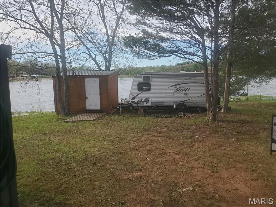 Waterfront lot in a gated community positioned perfectly for incredible unobstructed sunsets. This lot is right on the water and includes a 2014 Jayco Jayflight Swift 185 camping trailer, a combo storage shed/outdoor kitchen with mini fridge and cookstove.  Enjoy the serenity of this quiet lot while enjoying a meal or beverage out on the deck at the water's edge. You're just a short walk to the beach with a couple of pavilions and a dock out in the water. Check out the website for more information and restrictions here - https://cedarlakemo.com/
Pontoon is not included in sale but can be negotiated as personal property. Some photos are dated. Camper has been power washed.