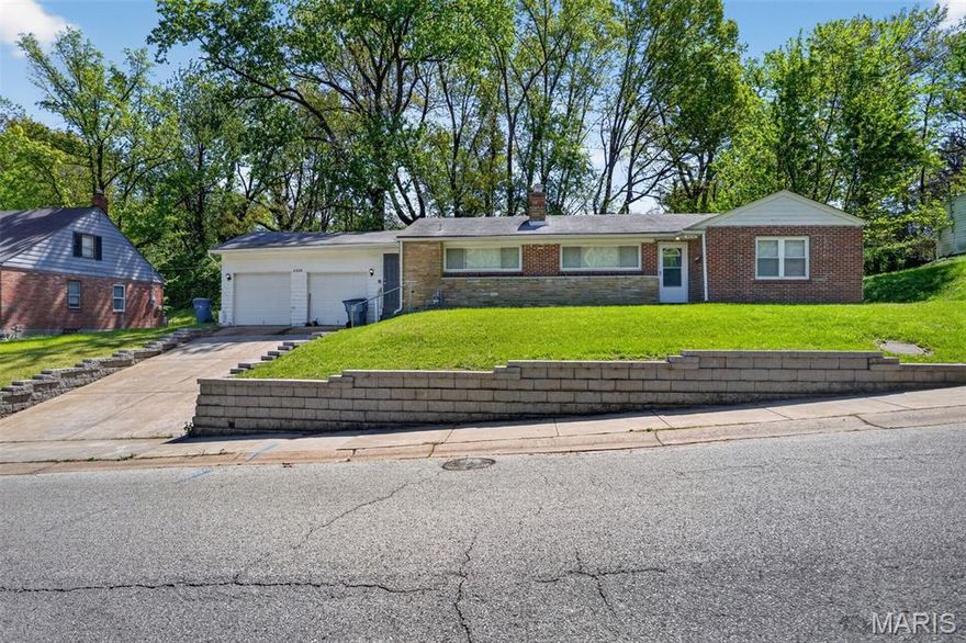 Charming 2-bed, 1.5-bath brick bungalow on a massive 0.34-acre level lot! This Northwoods gem features original hardwoods, a separate dining room, and a cozy living room with a brick fireplace. Standout amenities include a rare, oversized 2-car attached garage and a full basement ready for your finishing touches. Conveniently located near UMSL and I-70. Perfect for homeowners and investors alike