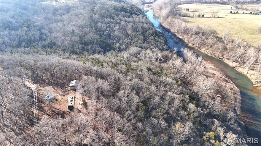 Well maintained park like setting with Big River frontage, sale includes a pole barn to keep your vehicle, boat or side x sides out of the weather, along with two small sheds being used for cabins. The front part of the property is approximately an acre that lays relatively flat and would easily accommodate a home as your new residence or a weekend getaway on a well maintained road. There is 220 underground electric in place with utility poles along the road. No need to haul water as there is already a drilled well. Spend the evenings around the large fire pit on a concrete patio and catching smallmouth bass on the river, located just 5 miles to dollar general, and 3.6 miles to Browns Ford park (boat ramp)
There is a $200.00 annual road maintenance fee