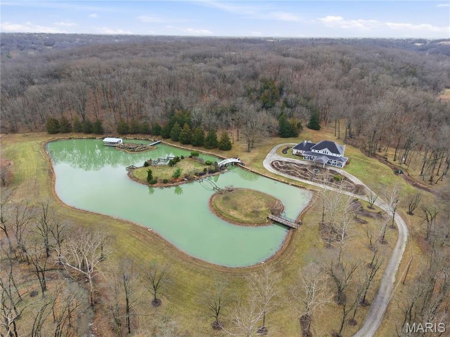 Welcome to your Dream Retreat in Columbia, Missouri!

Nestled on 26 breathtaking acres, this one-of-a-kind property offers the perfect balance of luxury living and incredible outdoor recreation. The land features a beautifully stocked private lake complete with islands and charming bridges, creating a stunning centerpiece that feels like your own private resort. The property is also loaded with deer and turkey, making it an exceptional retreat for wildlife lovers and outdoor enthusiasts.

The 7,500± square foot custom home has been meticulously cared for and is filled with high-end features throughout. From the moment you step inside the granite entryway, you’ll appreciate the craftsmanship and attention to detail, including hand-scraped teak floors, a stunning curved staircase, and two fireplaces. The home offers four spacious bedrooms and five bathrooms, along with a quiet study, large office space, abundant storage, and an attached three-car garage.

The fantastic kitchen is built for both everyday living and entertaining, featuring a Wolf gas stove, high-end appliances, a hidden pantry, and generous storage space throughout. Just off the main living area, the sunroom provides the perfect place to relax and watch the wildlife, overlooking the incredible scenery this property has to offer.
The luxurious master suite includes a spa-like bathroom equipped with heated floors, TV, coffee maker, and refrigerator, as well as a large walk in closet. 

The finished basement is designed for entertaining, featuring a spacious entertainment area along with a bar and small kitchen, making it the ideal place to host guests, watch the big game, or unwind after a long day.
Outside, the property also includes a large two-story outbuilding with potential living quarters, providing endless possibilities for guests, a workshop, or additional storage. 

This rare 26 +/- acre estate truly offers the best of both worlds — a private paradise retreat with incredible scenery, wildlife, and recreation, all located just 7 miles from downtown Columbia. Opportunities like this are incredibly rare!