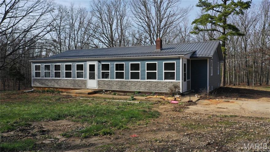 Spacious, move-in-ready family home offering 1,854 sq ft of finished living space on 5 wooded acres, conveniently close to town in the R-80 School District. Step into a large, light-filled living room that welcomes you home. The roomy kitchen features new cabinets, luxury vinyl plank flooring, and an electric range—perfect for everyday living and entertaining. This home feels nearly new with extensive updates including most flooring, fresh paint throughout, a new primary bath, updated light fixtures, some plumbing, new water heater, newer metal roof, and updated vinyl siding. Enjoy the convenience of main-level laundry, a full walk-out basement, and a primary bedroom with ensuite showcasing an updated surround, vanity, and commode. Relax on the finished, enclosed front porch—ideal for morning coffee or hosting guests. Well water and lagoon. Plenty of room to spread out and grow, both inside and out. Schedule a private showing today!