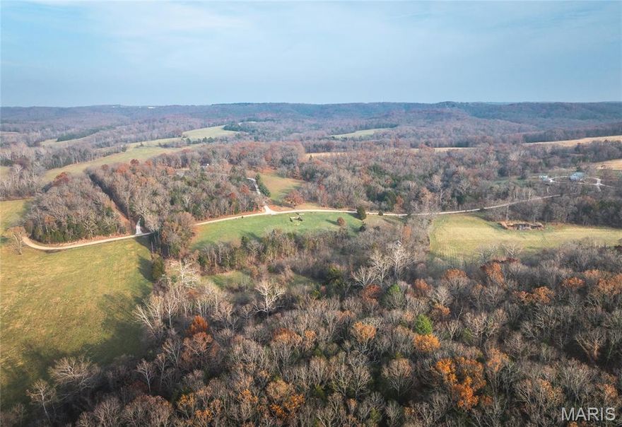 Welcome to an exceptional 183 +/- acre property in Maries County, offering a stunning mix of rolling hills, open fields, mature timber, and two spring-fed creeks that run year-round. Located just off Highway 63, north of Rolla and within the Rolla School District, this is a rare opportunity to own a premiere country estate with abundant space, privacy, and versatility. The 5-bedroom, 4-bath Cape Cod–style brick home (brick on all four sides) is accented with attractive rock trim at the front and side entrances. Inside, the formal dining room and study both include closets and can easily serve as additional bedrooms if needed. With 3,620 finished sq ft plus 2,020 unfinished sq ft, the home provides a total of 5,640 sq ft of usable space. The basement features a finished great room/game room, a cellar, a workshop equipped with three 8-ft heavy-duty workbenches, and additional storage space with heavy-duty shelving. Upstairs, the second floor includes walk-in attic access at both ends of the home for convenient storage or potential expansion. A remarkable 60' x 30' all-metal outbuilding offers unlimited possibilities—fully insulated and heated with three ceiling-mounted propane heaters (tank outside), concrete floors, air compressor with nine outlets along the building, built-in heavy-duty fold-up shelving, and numerous electric outlets for equipment or hobby use. Additional improvements include a rock wellhouse containing a second well with hand pump—sealed and fully functional without electricity—plus extra storage. A new Owens Corning Duration roof was installed on both the home and wellhouse in December 2024. Outdoor amenities are abundant with multiple living and picnic areas, a 44' x 30' concrete basketball court (also ideal for a future building pad or pickleball court), and a 150-yard shooting range complete with berm and distance markers at 40, 50, 100, and 150 yards. This property offers an extraordinary blend of natural beauty, privacy, and functional improvements—ideal for a full-time residence, recreational retreat, or multi-use country homestead.