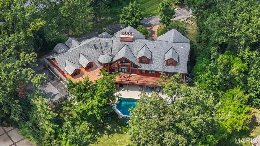 Experience an extraordinary private retreat in Town & Country, nestled within the highly sought-after Ladue School District. This masterfully crafted 7-bedroom, 6.5-bath estate spans over 9,000 square feet, where soaring vaulted cedar ceilings and dramatic floor-to-ceiling windows flood the interiors with natural light, all centered around a stunning double-sided fireplace. The custom chef’s kitchen is a true showpiece, boasting premium appliances, dual dishwashers, and an oversized island—ideal for both culinary artistry and casual gatherings. Every detail has been thoughtfully designed, from the spacious loft with play zones and a private media room to the guest suite with its own entrance and a walk-out gym featuring a built-in Ninja Warrior course. Two opulent primary suites (one on main and one on upper level) each provide a spa-like escape, complete with steam showers and jetted tubs. Plus a second bedroom suite/office on main. Step outside to a newly reimagined backyard oasis—your own resort-style haven. Enjoy the heated saltwater pool, outdoor kitchen, dining pavilion, and fire pit  lounge, all set within lush, professionally landscaped privacy. Blending refined elegance with unparalleled amenities, this one-of-a-kind residence offers the perfect balance of sophistication and vibrant, active living for the most discerning buyers.