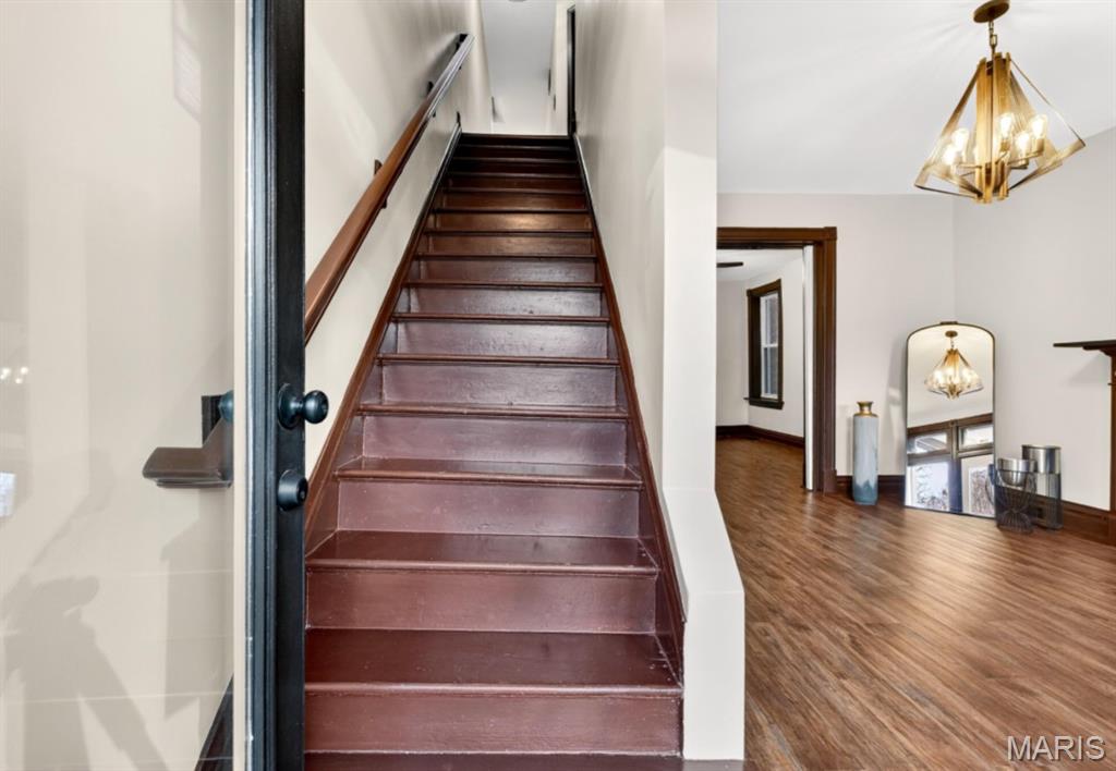 Stairs featuring a chandelier and wood finished floors