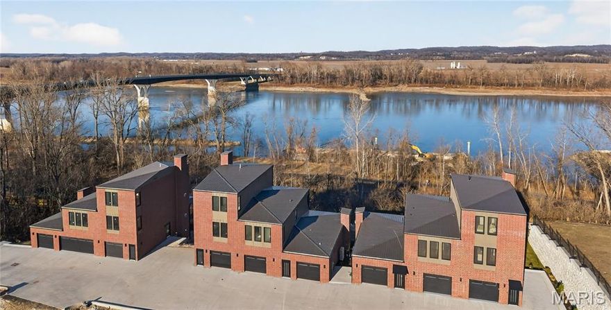 Welcome to The Bluffs at Bassora Place! This extraordinary, modern, 2,540 sq. ft., two-story townhome is perched on a scenic river bluff, where nature meets contemporary living in perfect harmony. From the moment you arrive, the architectural vision becomes unmistakable. Imported tilt-and-turn windows—a European hallmark of innovation & engineering excellence—frame the breathtaking Missouri River views. Every outward glance becomes a living masterpiece as nature’s timeless beauty unfolds before you. Step inside & discover an unwavering commitment to quality at every turn. The wide-open main level showcases true modern living with its seamless living/dining/kitchen design—an entertainer’s dream. Double doors open to an expansive deck, ideal for outdoor dining, hosting guests, or simply watching the boats go by. The kitchen is a standout feature, centered by a massive breakfast bar offering casual dining & abundant under-counter storage. Luminous quartz countertops define the space, while premium included Bosch appliances stand ready for culinary adventures. A well-designed butler’s pantry adds both storage & function—perfect for a coffee station—and cleverly tucks the refrigerator out of sight to maintain clean, uninterrupted kitchen lines. A stylish powder room & a stunning gas fireplace anchor the main living area, casting a warm glow on cool evenings. The lighted staircase guides you to the private upper level, where two luxurious bedroom suites await. The primary bedroom is a sanctuary unto itself. Here, sunrises & sunsets over the river create a beautiful start & end to the day. The ensuite bathroom exceeds all expectations with radiant heated floors—imagine stepping onto warm, sun-kissed tile even on the coldest mornings—along with an exquisitely tiled shower, relaxing soaker tub & double vanity. A thoughtfully designed custom closet system completes the space. An included Electrolux washer & dryer conveniently located in the hall, services both suites with ease. The fully finished walk-out lower level expands your living possibilities. With a full bath included, the space can function as a 3rd bedroom, a recreation room, or an office—your choice. Large windows ensure brightness, while the second gas fireplace adds cozy sophistication. Step out to the covered patio for additional outdoor enjoyment. Thoughtful upgrades are found throughout: zoned heating & cooling, engineered hardwood floors & a two-car garage equipped with an EV charging station & epoxy flooring are just a sampling of the exceptional features this home offers. The location adds yet another layer of appeal. Mercy Hospital is nearby, as is historic downtown Washington, dining & shopping. The Missouri River Bridge—your gateway to the region’s celebrated wine country & the Katy Trail—is just moments away. This is more than a residence. It is an invitation to live where exceptional craftsmanship meets nature’s majesty. Schedule your private showing today & discover what awaits you at The Bluffs at Bassora Place.