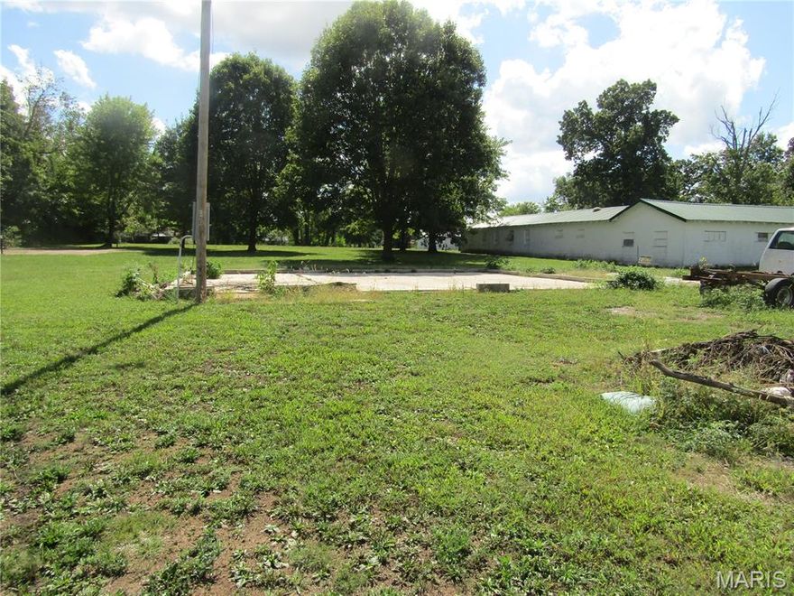 Very nice level lot located in the quaint Ozarks Town of Mountain Grove Missouri ready for a new build. There is a concrete pad already in place with water,sewer and electric hookups. Located on a nice quiet street beside a church and behind another new build, this is a great place to raise a family. There are 2 garages, a storage building and a cellar also on the property. The cellar could be easily converted into a storm shelter. One garage has a nice wood burning stove that could be plumbed into a new home. Great opportunity for an investment, residential home or rental property.