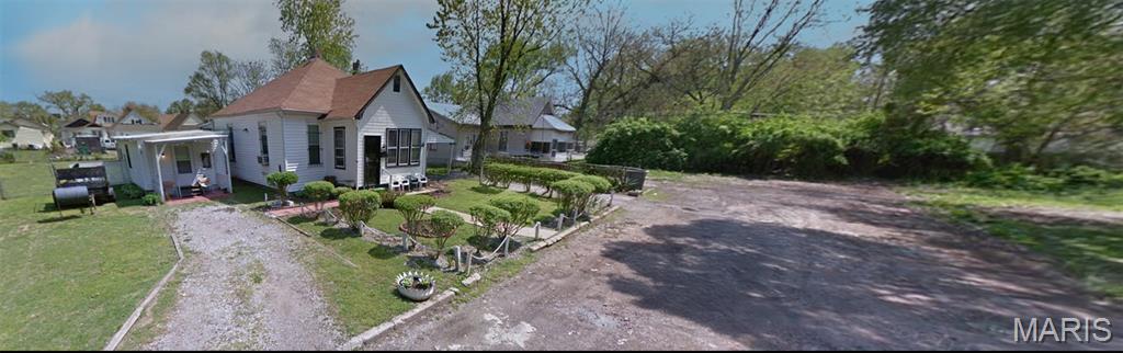 View of front of home featuring a front lawn and dirt driveway
