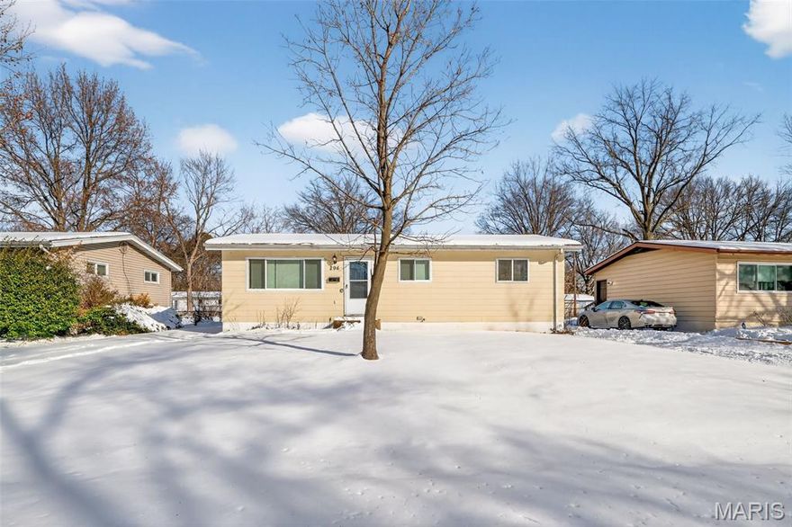 This single-level home offers a functional layout with inviting interior spaces and a spacious backyard. The exterior features light siding, mature trees, and a wide yard with room for outdoor enjoyment. Inside, hardwood flooring runs through the main living areas and bedrooms, complemented by neutral wall tones and abundant natural light from large windows. The kitchen includes white cabinetry, matching appliances, and ample counter space, with an adjacent dining area and sliding glass doors to the yard. A full bath with tub surround and an expansive unfinished basement provide additional storage and potential.