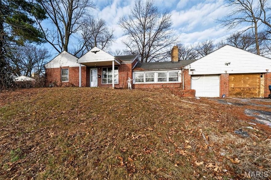 Spacious brick ranch set on a large, tree-lined lot with mature shade trees and plenty of outdoor space. The home features classic brick construction, a covered front entry, and an extended driveway leading to a detached garage for additional parking or storage. A wide front window brings natural light into the main living area, while the covered side patio provides a sheltered outdoor space for relaxing or entertaining. The expansive yard offers ample room for outdoor activities, gardening, or future landscaping possibilities. With its generous lot size and single-level layout, this property presents a great opportunity to create a comfortable home with room to personalize.