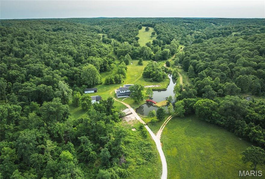 Own a rare piece of paradise with stunning 270 acres featuring your very own private gravel bar on the Upper Meramec River. This exceptional property boasts is a blend of lush pasture and mature timber, and multiple barns, ponds, and river—making it ideal for horses, cattle, or an ultimate recreational retreat. Anglers will appreciate world-class trophy smallmouth and largemouth bass fishing, along with some of the finest goggle-eye fishing in the Ozarks. Just a short drive to Maramec Spring Park. Wildlife abounds, with large whitetail deer and thunderous gobblers filling the landscape. A spring-fed pond in front of the house, complete with a classic bridge. The property offers a bunkhouse/guest cottage for visitors, a large barn/warehouse-style building to store equipment, UTVs, a lodge-style main home, built with impeccable attention to detail, offering multiple beds and baths—perfect for hosting guests with a rooftop deck and covered porch for breathtaking views.