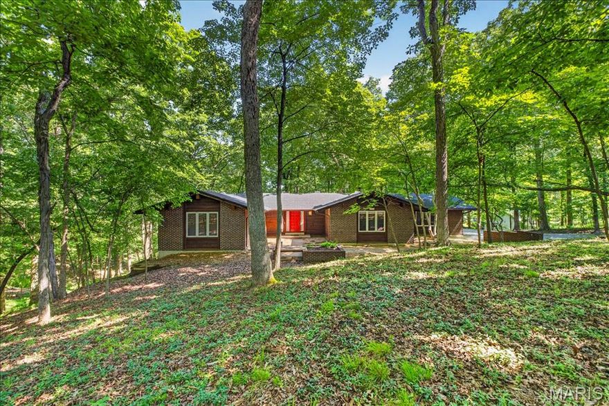Experience the perfect blend of peace, architectural style, and unmatched entertaining potential in the highly sought-after Indian Tree subdivision. Situated on a sprawling, secluded 3.1+/- acre lot surrounded by mature trees, this custom mid-century home offers a private country feel just minutes from modern conveniences. 3,599+/- SqFt, 4 bedroom, 3 full bath home featuring mid-century exterior components of a low pitch/gentle slope roof, clean lines, and a variety of exterior finishes of brick, cedar and color. Partially covered front porch greets you as you step inside the open floor plan. Mostly job-finished, wood flooring throughout the main level. Spacious, eat-in kitchen featuring custom cabinetry, granite countertops, center island w/breakfast bar, open to lower level & glass walk-out to deck allowing plenty of natural light. Adjacent dining room with crown molding & chair railing. Primary suite with floor-to-ceiling fireplace, Juliet balcony, multiple closets, glass walk-out to private deck, single sink vanity, private commode & shower/tub. Two additional bedrooms, 1 w/carpeting, bi-fold closets & share hall full bath. Walk-out lower level extends living quarters boasting a living room w/16’+/- ceiling to main level, floor-to-ceiling fireplace, wet bar & a sliding glass door walk-out to large patio. 4th Bedroom, full bath, 2 rec rooms, storage room & unfinished laundry/storage room completes the lower level. Outside, you will enjoy an AWESOME gently sloping lot surrounded by lush/mature trees & a 2-car attached garage. Country living just minutes from Wildwood Town Center and easy access to shopping, parks, Manchester Road, and AAA Rockwood schools. From intimate dinner parties to large-scale celebrations, this architectural gem is ready for its next host. Schedule your private tour today!