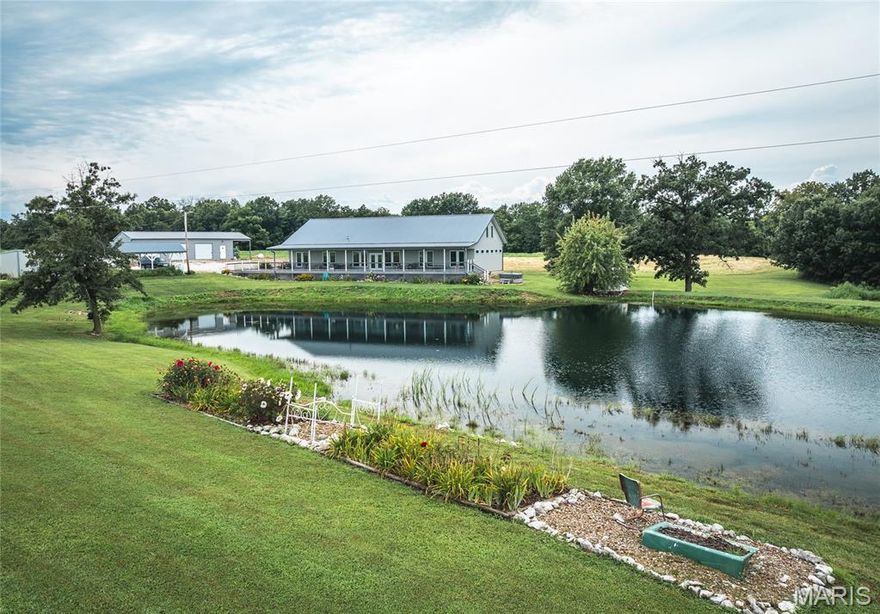 Drive through the gates and follow the lane as it opens to a breathtaking view  a beautiful home across the water, perfectly framed by a ¾-acre stocked lake. This 10 acre property offers a harmonious mix of  open land and enough timber for hunting. Surrounded by rich agricultural fields,  these woods are home to trophy-class North Missouri bucks and abundant wild turkey. The stunning 5-bedroom, 6-bath residence boasts an 80-foot covered front porch overlooking the lake, where you can watch large fish swimming just below the surface. Inside, an open-concept living and dining area with a cozy fireplace flows into a chef’s kitchen featuring custom cabinetry, quartz countertops, and an impressive 6' x 12' island — perfect for gatherings. A large walk-in pantry with ample shelving keeps everything organized, and the master suite includes a whirlpool tub for relaxing after a long day. Previously used as a vacation rental, the home is equally suited as a private retreat or full-time residence. The property also includes  two productive garden spots with rich, loamy soil, a pavilion by the lake, a three-car detached garage with workshop, and an additional carport. Located just 8 miles from the Mississippi River and Fenway public access, this property offers both seclusion and convenience — a rare opportunity for those seeking beauty, recreation, and income potential all in one.