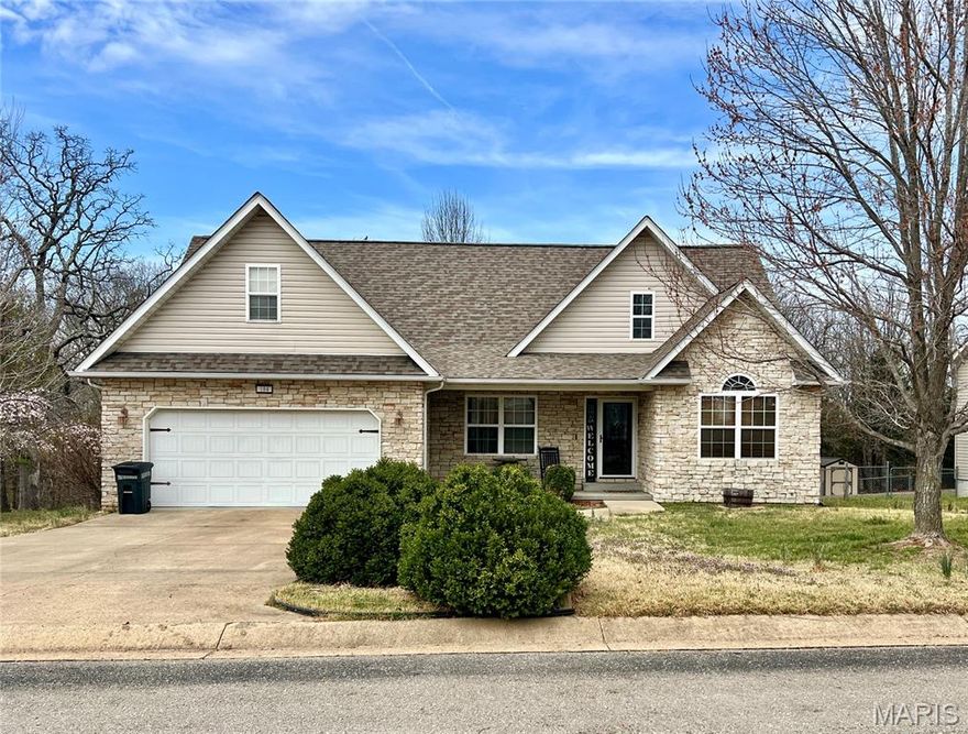 Welcome home to this stunning 4-bedroom, 2-bath stone-accented beauty nestled on a half-acre lot in Waynesville! From the moment you pull up, the gorgeous stone façade and manicured landscaping set the tone. Step inside to rich hardwood floors, soaring vaulted ceilings, and a warm gas fireplace that anchors the spacious living room. The dining area features a charming tray ceiling and flows effortlessly through the open layout. The primary suite is a true retreat — complete with a tray ceiling, walk-in closet, and private en-suite bath. Granite countertops, quality finishes, and thoughtful details throughout. The oversized 4th bedroom/flex space upstairs offers endless possibilities — home office, bonus room, media room, or guest suite. Enjoy outdoor living on the covered front porch or the large covered back patio. Two-car garage, half-acre lot, great neighborhood and move-in ready. This one checks every box!