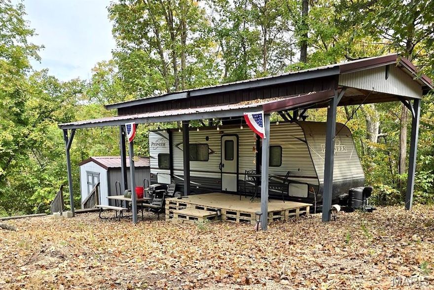 Fully setup and ready for your camping and fishing adventures. Half acre waterfront camping lot on Cedar Lake. 2017 Pioneer 28 foot bunk house camper, kept under permanent RV carport. Private 220 amp electric service on property, along with 200 gallon above ground water tank and 100 gallon above ground septic tank. Gravel section on lot can be used for parking or entertaining. Seller has installed retaining wall, fire pit, and a path to the water's edge. 12x12 storage shed has electricity, interior shelving and work bench. Enjoy fishing and relaxing on this recreational lot. Located in a gated community. Additional Rooms: In Platted Subdv.