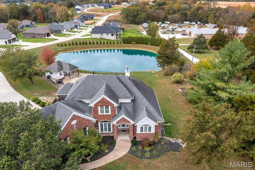 Nestled on over 3.5 beautifully landscaped acres in the heart of Foristell (Wentzville Schools), this stunning traditional 2-story home of red brick and white siding welcomes you with timeless charm and a sense of peaceful privacy.
Step through the front door and into a soaring two-story living room, where sunlight streams through expansive west-facing windows, revealing breathtaking views of the pool, pond, and wooded backdrop beyond. A double-sided fireplace warms both the living area and adjoining spaces, creating an atmosphere that’s both grand and cozy.
The kitchen is designed for those who love to cook and gather — featuring granite countertops, a large island, ample cabinetry and pantry, and abundant counter space. Adjacent to the kitchen, the breakfast room easily accommodates large gatherings (seating up to twenty!) and opens to a screened porch, perfect for morning coffee or summer dinners outdoors. A formal dining room, framed by the elegant two-story entry, adds just the right touch of sophistication for special occasions.
Your main floor primary suite is a true retreat, complete with fireplace and panoramic windows overlooking the property and a private deck to enjoy sunsets. The primary bathroom feels like a private spa — boasting a soaking tub, separate oversized shower, and dual vanities. 
Ascend the grand staircase to find two generous bedrooms connected by a Jack-and-Jill bath, each offering comfort and space to unwind.
The walk-out lower level is designed for entertaining and relaxation. Step out directly onto the pool deck, or enjoy the comfort of the second full kitchen — perfectly positioned to serve indoor and outdoor guests. A spacious family room with another double-sided fireplace anchors this level, shared with a large bedroom suite featuring excellent natural light and a luxurious second primary bath with a soaking tub, separate shower, and double sinks. There’s also a flex room ideal for a media area, office, or guest space (non-conforming bedroom), plus a half bath, laundry area (laundry room options on main floor and lower level), and abundant storage.
Outside, the magic continues. The sparkling pool invites endless summer fun, while the expansive deck, built-in gas grill, and firepit area make entertaining effortless. The pool house includes a half bath and refrigerator, ensuring everything you need is close at hand. Beyond, the stocked pond glistens in the afternoon sun — and if you bring food, the fish will happily come to greet you.
This property is more than a home — it’s a lifestyle. Private. Serene. Spacious. A true retreat, yet just minutes from the conveniences of Wentzville and Foristell. All appliances stay, making your move seamless and your new beginning simple.  Come see for yourself how it feels to live where every day ends with a sunset over the water.
Your peaceful Foristell retreat is waiting.