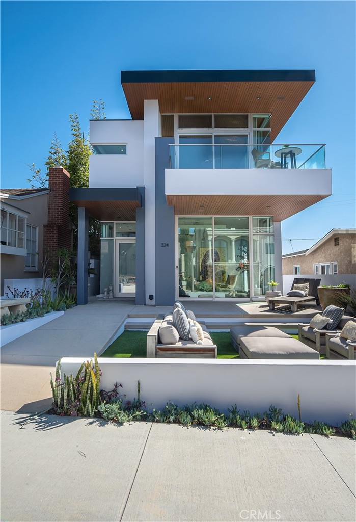 Rarely does an opportunity arise to purchase an architecturally significant, modern estate perched high above the Pacific on a coveted walkstreet in the heart of Manhattan Beach. Boasting panoramic ocean views and luxurious living on every level, this home is a true showcase, designed by Michael Lee and offering four bedrooms and four-and-a-half baths in 3634 square feet. The showstopping top level is an entertainer’s dream, with 11-foot teak ceilings allowing for a flood of natural light throughout, and stunning water views from several vantage points. A formal living room with glass-encased balcony and fireplace, seating area as well as a formal dining room bordered by walls of windows and anchored by bamboo floors are found at the top of the floating stairway. The large, modern kitchen features hardwood cabinetry and a generous center island, granite countertops and Bosch appliances, as well as a built-in wine fridge and nearby powder room. Step through the glass doors and out onto an airy patio, complete with built-in fireplace and protected dining area with lovely views of the Pacific. The bonus room is the perfect game / media / family room, with corner windows to take in additional views and allow for plenty of sunshine. Downstairs, a family room opens onto a sizeable walkstreet patio, complete with concrete decking and a turf yard – all placed to take advantage of the incredible vistas. This floor also includes three bedrooms and three full baths, all with contemporary fixtures and finishes and slate floors. The primary suite is tucked away down the hall and provides the perfect sanctuary with sparkling water views, a huge spa-like primary bath with separate shower and soaking tub, as well as a big walk-in closet. On the first level, another bedroom and bath offer guest quarters, while a laundry room provides a myriad of storage options, and a three-stop elevator is optimally placed near the three-car garage. Two additional parking spaces allow for a total of five cars, almost unheard of this close to the beach. Located just three blocks to the Strand and a brief walk to downtown Manhattan Beach, this home has location bragging rights as well. An impressive feat in design and architectural style, this residence is truly one-of-a-kind, offering the finest oceanside living available today in this storied seaside town.