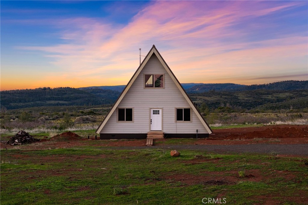 Welcome to 4614 Wilder Drive, a property filled with picturesque views and stunning sunsets located just 20 minutes from Chico! You will marvel at the scenic drive on your way to this darling half built A-frame beauty with 4 independent custom outbuildings where all your future custom home visions can come to life, all nestled against a million dollar view. On your way to this gorgeous property you will cross streams, cow pastures, and storybook landscapes that look otherworldly. When you pull up to the gravel driveway you will find a perfectly graded lot that leads to the home and several outbuildings bordering the property. The darling A-frame cabin itself boasts 1200 square feet of living space with plans for a 1 bed (with walk-in closet)/1 bath (with space for a stackable washer and dryer) tiny home with open concept kitchen, and a large loft. You will gasp when you see the floor to ceiling picture windows off the open concept kitchen, living area and loft with unobstructed views. The home is fully framed with a concrete foundation, new metal roof, new hardy back siding, new dual pane windows, and a wood burning stove for heat. The kitchen and bathrooms have all their plumbing infrastructure in place, but for needing the finishing touches. The property boasts a 1500 gallon, 2 chamber poly infiltrator septic that can support 4-5 bedrooms for expansion of the home or property. The community well professionally operated by Del Oro water is a prolific producer at 900 feet deep. Step into the fully enclosed, deer proofed garden and miniature orchard where 3 independent out buildings with power exists for comfortable living while your construction plans come to life. One outbuilding operates as a tiny bedroom with a tiny wood burning stove for heat. Another outbuilding is being used as a meal pre station. The third as a pottery making station with a kiln and storage. The fourth outbuilding is perfect for extra storage. These spaces are all tied together beautifully with stamped concrete patios and several custom pergolas. You will also find an enclosed bathing station that offers a clawfoot bath tub and stand up shower. Both with hot water from a propane water heater. Take a hot bath in the claw foot tub and look out onto the mini orchard and raised garden beds with the backdrop of raw wilderness. This property is truly a marvel to behold!