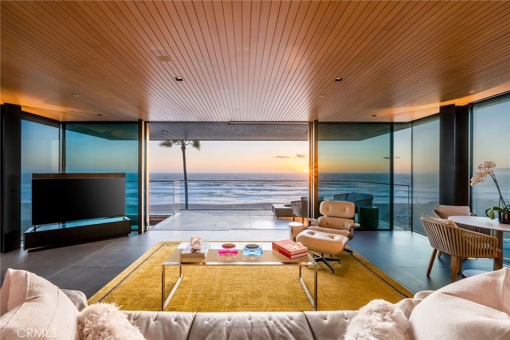 In dreaming, designing, and executing this truly irreplaceable 5-story oceanfront property by Michael Lee Architects, all elements have been expertly woven together into the ultimate representation of absolute perfection. Earth, air, fire and water stand in a visionary blend of architecture, function, and timeless presence forever making a unique statement along one of the most sought after stretches of coastline in the world. The facade is bold and beautiful, dressed in durable micro-layered Richlite wood and R100 privacy glass, then subtly trimmed in steel. Sitting proudly overlooking expansive views of the horizon which stretch from Palos Verdes and Catalina to the Malibu coastline. Watch endless world-class surf in El Porto from one of the very best vantage points in all of Manhattan Beach - the private, open concept living room perched high above the Strand. Walls of floor-to-ceiling glass capture the shifting moods of the ocean presenting a different backdrop almost hourly. Open the room-height German-made Schüco 77 sliding doors to welcome the ocean air and expand the living area onto the deck beyond, where you can enjoy dramatic sunsets while soaking in your solid copper spa! The modern kitchen is outfitted with a full suite of premium appliance brands: Gaggenau, SubZero and Meile. Pantry shelving and appliance storage options are expertly designed right into the sleek cabinetry custom made by Design Support Woodworking. A 3-sided glass Ortal fireplace expands views of the ocean while seated at the custom built-in dining table. The master suite showcases front-and center views, blackout curtains, and switch glass in the master bath. Dramatic and discreet up and downlighting is used extensively throughout. This custom home holds numerous surprises, such as a media room with nearly 20 foot ceilings, a 2-story green wall and koi pond, top of the line Crestron automation, a four-stop, Italian-made glass and steel elevator from Elevator Boutique, 6 zone HVAC, full interior walk-in surf shower, a car lift-ready garage, a whole house water filtration + three 17 stage reverse osmosis systems, and radiant heat on all 5 floors, as well as both the master balcony and the top floor balcony decks. An innovative home office features a custom sit-stand desk with a large glass black board. Guests benefit from plenty of bonus parking nearby. Walk down the steps from the Strand onto the beach and straight out to some of the best surf in Southern California!
