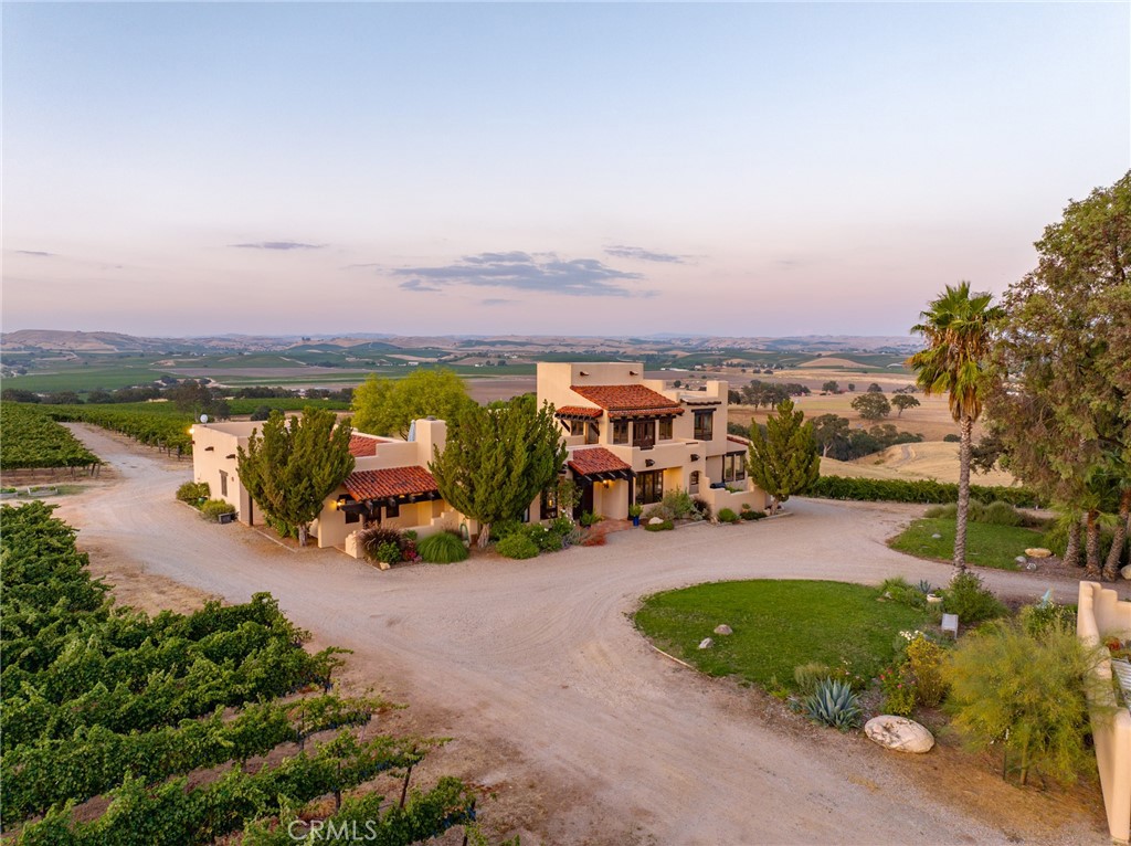 Wine country estate perfectly situated on 52± acres overlooking the lush vines of the Paso Robles appellation. With unobstructed views of the 28.5± planted acres of Cabernet Sauvignon and mesmerizing sunsets. The unique parcel offers a 3,869± sq.ft. home, horse barn with stalls with attached one bedroom casita suite, approx. 4± acres of horse pastures. The impressive entry sets the tone with Travertine flooring, exposed beams, and breathtaking views from the surrounding windows. With an open concept design the dining room and living room welcome you into the upgraded kitchen with plenty of space for all your entertaining needs. The kitchen features custom native black Walnut cabinetry, Viking 6 burner stove and double ovens, under counter microwave, Sub-Zero refrigerator, granite island and quartz countertops. Enjoy the views from the kitchen dining area with direct access to the patio. Custom touches continue onto the primary suite with recently upgraded Travertine flooring, carpet, lighting fixtures and radiant heated floors, soaking tub, custom vanity and frameless shower in the luxurious primary bathroom. The captivating custom home also showcases a dedicated office, laundry room, art gallery, wine cellar and private outdoor patio with roof top seating. Additional property highlights include a shop building with roll-up doors, (2) 12x12 horse stalls, ag and domestic wells, solar array which supports the complete vineyard/ranch, and solar powered entry gates. Property benefits from lower taxes under the Williamson Act. Every direction is greeted by vines and the elegance of the architectural elements set in the heart of Paso Robles.