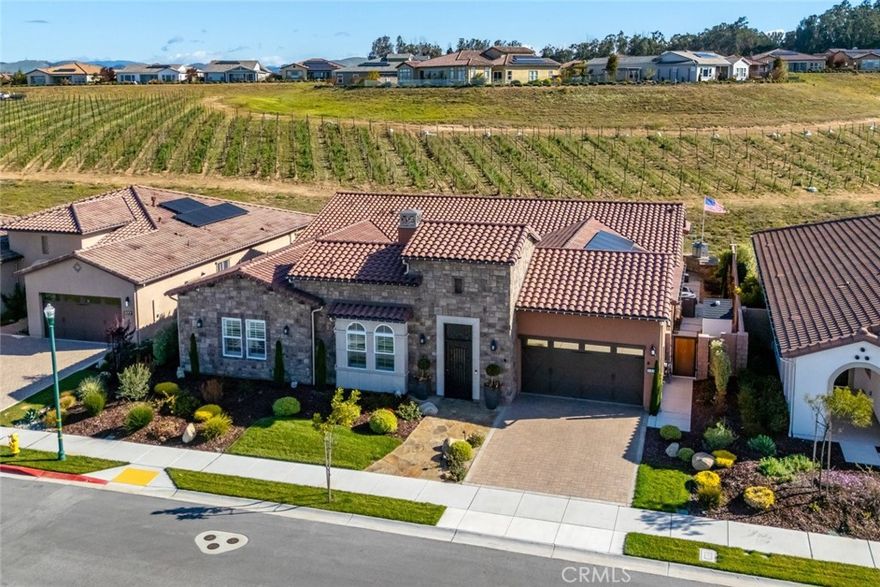 Welcome to this majestic, nearly new, Dolcetto Estate home with a spectacular 180-degree vineyard view, surrounded by stunning flagstone hardscape and lush landscaping. Built in 2022, this magnificent 3 bedroom + Den, 3.5 bath home offers 3,563 sq. ft. of impeccably designed living/entertaining space where no expense was spared. Enter through the enclosed courtyard with beautiful flagstone floors, a stone fireplace and French doors on three sides - it’s sure to be your private “go-to” place to relax. Inside, you’re met with sweeping views through the many windows/transom windows and the rolling wall of glass which unite the inside with the great outdoors - the backyard features a built-in fire pit, barbecue/kitchen and your own private putting green - this is Trilogy living at it’s best! And, that’s just the tip of the iceberg - starting with the impeccably designed culinary kitchen, you’ll love the rich raised-panel cabinetry with multiple pot drawers, top-of-line Wolf stainless steel appliances, including double wall ovens and a 6-burner gas cooktop with industrial stainless hood, Sub-Zero built-in refrigerator, gorgeous quartz countertops and large T-shaped island with modern pendant lighting and seating for 8, plus a walk-in pantry - it’s a chef’s dream! Surrounding the kitchen is a wraparound great room with stone fireplace, built-in lower cabinets and a spacious dining space with a striking custom chandelier - it’s bright, airy, and the views are outstanding. The private owner’s suite has a super spacious bedroom with custom chandelier, sleek power window shades, sitting area and direct patio access. The master bath is luxury personified - stunning tile shower with wraparound glass enclosure, Roman tub, separate dual sinks, vanity, linen storage, plus a massive, customized walk-in closet with convenient pass-thru to the laundry. Beyond are two guest bedrooms, both with walk-in closet and full en-suite bathroom with shower and exceptional finishes. Additionally, there’s an office, powder room, upgraded ceramic tile flooring, A/C, SOLAR, and a 3-car tandem garage with showroom epoxy floors, and upper storage rack. You may never want to leave this gorgeous home, but when you do you’ll have access to all the resort style amenities Trilogy has to offer.