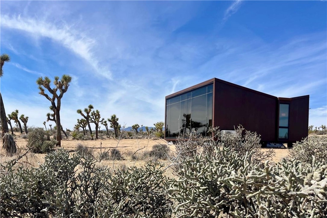 Welcome to EXPEDITIONS: A one-of-a-kind 34 acre master-planned project near Joshua Tree that stands out as the singular local high-end Landscape Units development plan – already initiated – with room to grow. Seller has prepared a preliminary subdivision map to eventually subdivide the existing 34-acre parcel into 9 lots, each accommodating two units, for a total of 18 units across a thoughtfully developed space. A comprehensive master plan is included, outlining building sites accessed by two county roads, ensuring seamless ingress and egress to each lot, with utilities already in place on both sides of the property. The two completed and fully installed homes in phase one of the development (dubbed Jupiter 1 & 2) are designed to harmonize with the rugged beauty of the desert. The two-bedroom, two-bathroom unit spans 792 square feet, while the one-bedroom, one-bathroom unit covers 528 square feet, both offering luxury living in a sustainable desert setting. Each home boasts a distinctive interior design inspired by Jupiter’s warm oranges, beiges, and earthy tones, paired with high-end finishes and designer furniture for a sophisticated yet welcoming ambiance. Proposed amenities in the master plan include private patios with hot tubs, firepits, BBQ grills, cowboy tubs, outdoor showers, daybeds, and hammocks, designed to offer an unparalleled indoor-outdoor lifestyle. Each unit’s massive reflective windows offer a private looking glass into the surrounding natural landscape, crafted for comfort with high-quality finishes, fixtures, and built-in features that evoke luxury space-age lounging. The project offers stunning mountain views and close proximity to local attractions like Joshua Tree National Park, Pioneertown, and the amenities of Yucca Valley, just 10 minutes away. Whether you’re seeking a personal retreat, an investment opportunity in vacation rentals, or a platform for a larger vision, EXPEDITIONS delivers limitless potential. Contact us today to explore this unparalleled offering and begin your journey into desert luxury.