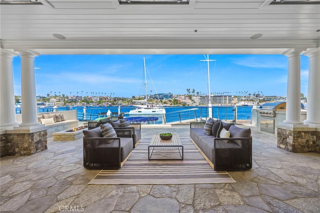 Nestled along the picturesque shores of Newport Beach, 2222 Channel Rd embodies the epitome of coastal living, surpassing every expectation. Situated on the esteemed Balboa Peninsula Point, this bay-front residence exudes timeless charm with its craftsman architecture seamlessly integrated into the breathtaking Newport seascape. From the moment you arrive at the inviting entrance, adorned with vibrant flowers and offering a sense of seclusion, the allure of this home is palpable. Stepping inside, the great room captivates with panoramic bay views, seamlessly merging the elegant kitchen, spacious living area, and inviting entertaining space. Adorned with coffered ceilings & meticulous millwork, every detail exudes sophistication. The gourmet kitchen, equipped w/ top-of-the-line appliances and a walk-in pantry, is both a chef's haven and a gathering place for family and friends. A vibrant fireplace anchors the expansive living area, offering a cozy ambiance while the bay unfolds its daily spectacle of sailboats and yachts gliding by.
Transitioning outdoors, a sprawling covered deck awaits, complete with a built-in BBQ, fire-pit, and private dock accommodating a Duffy boat. Completing the ground floor, a comfortable office with bespoke cabinetry offers a tranquil workspace. Ascend via stairs or elevator to discover a second living room or optional bedroom, two spacious secondary bedrooms with bathrooms, and a separate laundry room. The primary suite is a sanctuary unto itself, boasting a generous walk-in closet, a cozy seating area with a fireplace, and a bay-front balcony, offering a serene retreat for morning coffee or evening relaxation. The en-suite bathroom features separate double vanities, a luxurious soaking tub, and a stunning shower. Elevating the experience, a rooftop deck offers a breathtaking 360-degree panorama of the bay, Corona del Mar, and the glistening Pacific Ocean, complete with a jacuzzi spa for indulgent evenings under the stars. Additional amenities include a two-car garage providing ample storage space. Embrace the enchantment of this coastal haven with leisurely bike rides to cafes and restaurants, strolls to the Wedge Beach, access to the private bay beach and esteemed waterfront schools. Create cherished memories in a home that embodies the essence of Newport Beach living.