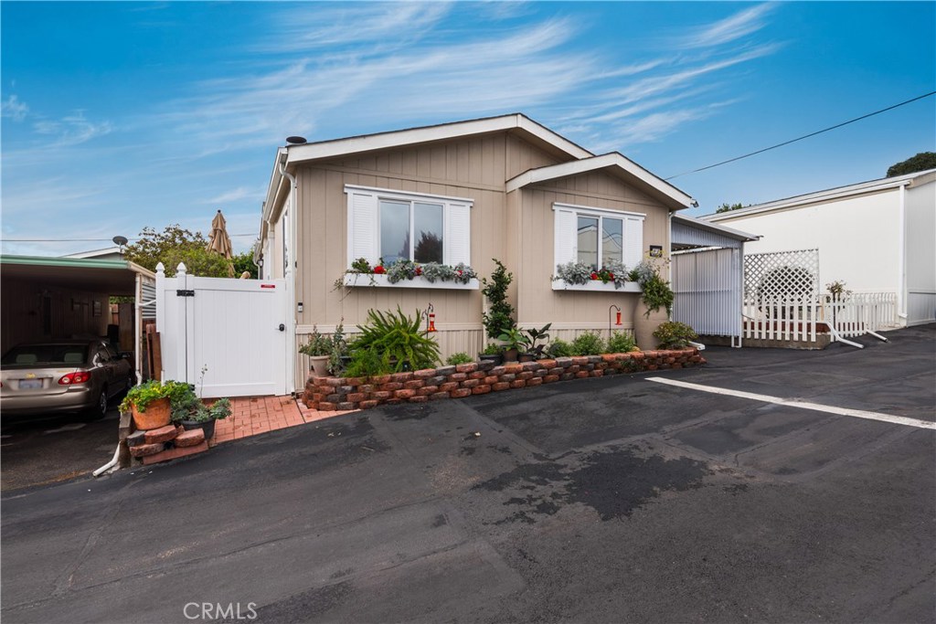 Perched atop the peak of Grande Mobile Manor in 55+ community, this turnkey 2002 manufactured home is in like-new condition and has soaring panoramic views of Arroyo Grande Valley from several rooms. New vinyl fencing with gates allow for maximum privacy – and a freshly installed Trex deck leads you to the front door. Upon entering you will notice the soaring ceilings, walnut hardwood floors and open concept living area with a wood burning fireplace and those views! The gourmet kitchen has a useful breakfast peninsula and is open to the dining and living areas. Two guest bedrooms and a bath are at the front of the home, while the master suite is separate and quiet at the back with a large master bath and walk in closet. Interior laundry leads to a private patio area off the carport screened by privacy fencing and lined with paver stone patios to create a large and quiet retreat with plenty of storage. The park boasts gorgeous grounds, including a community garden, guest parking and a community laundry room. Prolific lemon tree off the patio and home includes RO System. Call your favorite Realtor today to schedule your showing.