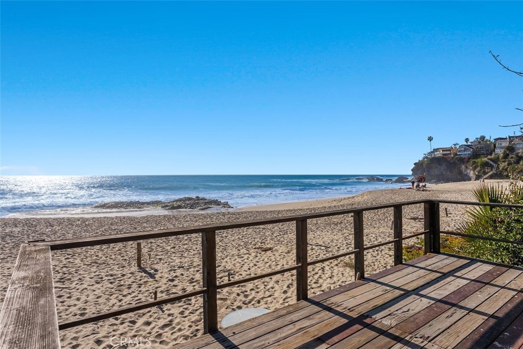 This incredible Laguna Beach oceanfront estate, designed by renowned architect Chris Abel, offers a rare combination of size, architectural excellence, privacy, and a deeded, roped-off private shoreline. As you enter the motor court through an electronic gate, you are immediately captivated by lush landscaping, breathtaking ocean views, and ample parking. Inside the main residence, panoramic ocean vistas greet you from the living room, professional-grade kitchen, and dining area. The dramatic post-and-beam design, complemented by oversized windows at every angle, creates a stunning visual experience. Directly off the living room, the first of six white-water ocean-view decks invites you to enjoy al fresco dining or take in the sunset year-round. Above the expansive living space, an oversized loft—ideal for an office or bonus room—includes a full bathroom. The primary suite features a spacious bedroom with direct deck access, an oversized bathroom, a walk-in closet, a sitting area, and a private office. Three additional guest bedrooms, an oceanfront deck, and a large laundry room complete the main residence. Connected by a dramatic spiral staircase, the guest house sits just above the sand, offering two bedrooms, one bathroom, a family room with a dramatic fireplace, a full kitchen, and a large oceanfront patio. From here, private stairs lead to the lowest deck and an exclusive sandy retreat. A truly rare feature in California, the roped-off private beach area allows for exclusive gatherings, barbecues, pets, and even adult libations—luxuries typically prohibited on public beaches.