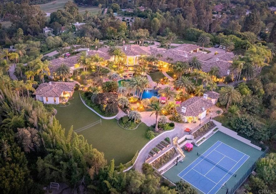 Offering the best of Rancho Santa Fe, this 6.65 all usable view acre estate excites the senses immediately as one enters the grand iron gates. True resort-style living with cascading waterfalls, Tiki-torch lined pathways, expansive pool & spa, outdoor pavilion, two guest houses, grassy play yards, volleyball court, tennis court with basketball court inset, vegetable gardens, and vistas to the Rancho Santa Fe golf course. The primary residence features all en-suite bedrooms, an elegant wood paneled office, resort size gym, playroom, game room, theatre, bar, and wine room. The 5,000+SF dedicated owner’s retreat situated on a private wing includes a sitting room, oversized his & her closets, her shoe closet, and private courtyard featuring a pool, spa, and fireplace. The gourmet kitchen would impress the most discerning buyer, featuring La Cornue, Calacatta gold marble, and top-of-the-line appliances. Just off the kitchen, the Great room opens beautifully onto the outdoor living room with doors completely disappearing into the walls to create a magnificent indoor/outdoor experience. When it comes to home automation and state-of-the-art home technology, this home has it all: distributed audio system that includes 28 zones, keypad or touch screen in nearly every room, and surveillance system that supports up to 64 cameras. This once-in-a-lifetime estate offers enjoyment in an environment that elevates one's health and well-being.