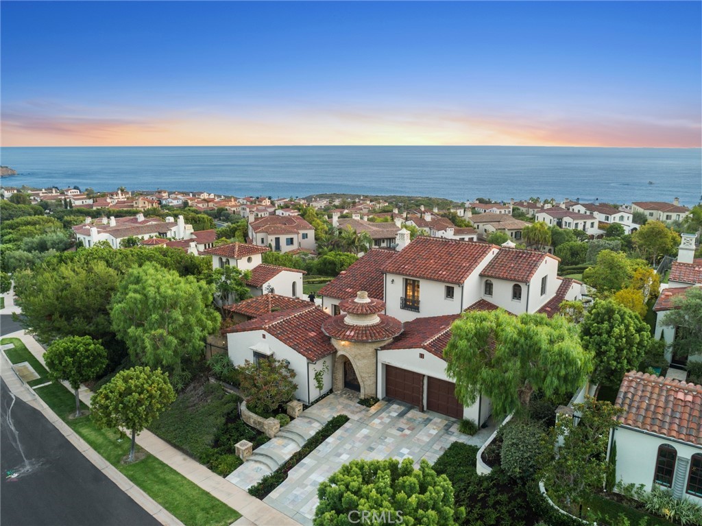 Stretched along an ocean-facing corner lot, with 210 linear feet of ocean view, this property has a rear lot line nearly 3x longer than the average of all homes along Archipelago, allowing for uninterrupted views of ocean swells, blue skies, fiery sunsets, and boats cruising the Pacific. Reminiscent of a Mediterranean villa, this upscale home welcomes guests with ease, offering 4,324 +/- s.f. with a total of 5 bedrooms and 4.5 bathrooms inclusive of the main house and 2 guest Casitas. In the main house, arched windows & doorways frame views and create an airy living & dining area, with timber beams adding rustic charm. An adjoining eat-in kitchen offers inspired culinary experiences, with a Viking 6-burner range, 3 ovens, water filtration, wine refrigerator, & granite-topped island. Wood panels line an ocean view lounge room with bar, and a main level master suite has a walk-in closet, fireplace, ensuite w/stone-topped vanity & soaking tub. Upstairs offers a sitting area, and 2 bright bedrooms connected by a full bath with separate vanities. Two guest Casitas each have 1-bed, 1-bath; a stand-out feature for hosting guests or extended family. One of the Casitas has views of a courtyard reflecting pool & fountain, and the other has stunning ocean views, a wet bar, & mini frig. Whole-house audio extends into exterior spaces that include a BBQ kitchen with frig & bar, and a cabana with a warming fire pit. Guard-gated Crystal Cove offers a pool, sports courts, resident-only Canyon Club access, and is walking distance from beaches, shopping & dining.