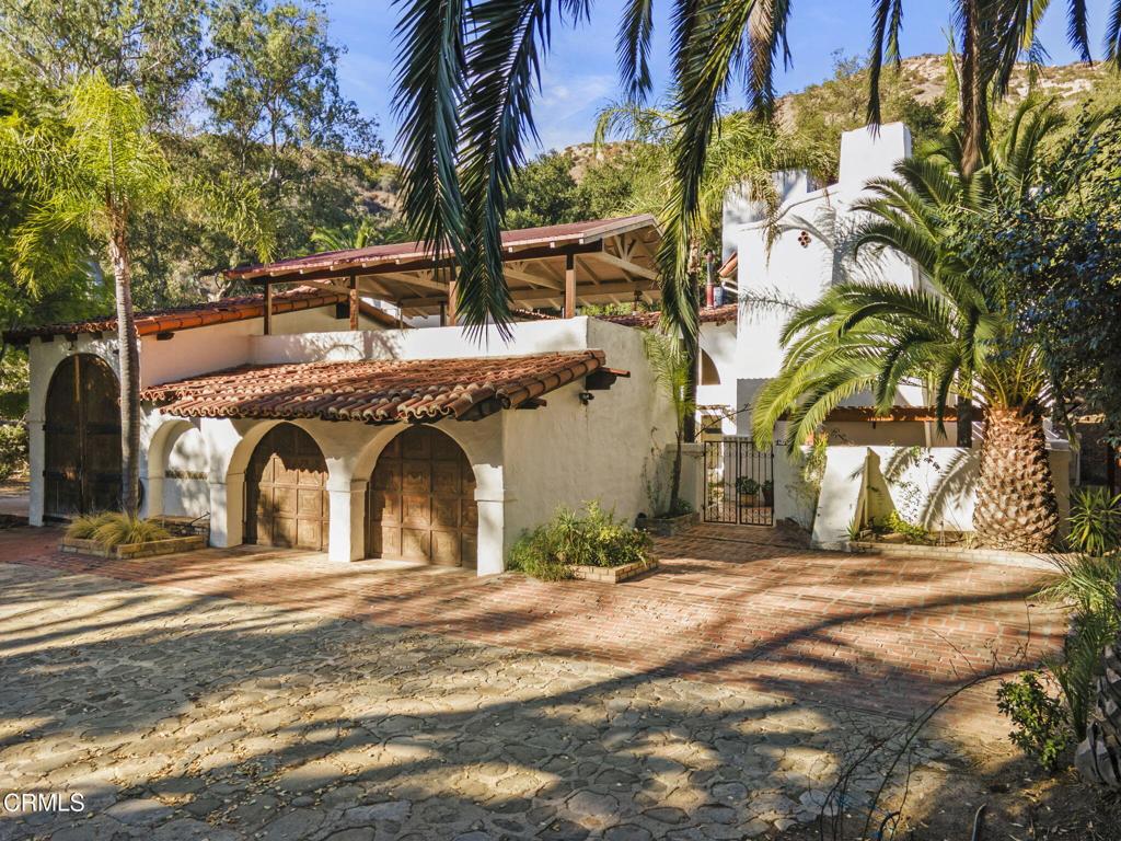 Chuhuichupa Ranch invites you to experience a tranquil, parklike setting where nature takes center stage. Nestled amongst mature oaks and teeming with deer and wildlife, this exceptional property offers the perfect blend of rustic charm and proximity to modern conveniences--located less than two miles from Downtown Ojai. As you approach this serene escape at the end of Ayers Avenue, a eucalyptus-lined drive leads you to a stunning custom-built home set against the breathtaking backdrop of conservation land. The top of the property provides direct access to the popular Shelf Road Trailhead and Valley View Preserve, offering endless opportunities to explore the beauty of the foothills. The ranch boasts incredible valley views from multiple vantage points, making it a peaceful retreat to recharge and reconnect with nature. The property spans 18.34 acres across five parcels, presenting unique development opportunities. The lower portion includes two primarily flat, nearly 1-acre parcels with residential zoning, ideal for creating additional residences or expanding the estate. This versatility makes the ranch an unparalleled investment for those seeking to create a custom compound or capitalize on its possibilities. At the heart of the ranch stands a 3,658 sq/ft Spanish Revival-style home exuding timeless elegance. Built with meticulous attention to detail, the home incorporates rare woods, jade-inlaid fireplaces, and Saltillo paver tiles, blending natural materials with thoughtful craftsmanship. The gated courtyard welcomes you with a tranquil fountain and leads to a viewing deck above the garage, providing stunning views of the property. Inside, an arched doorway opens to a warm and inviting entryway with a gallery wall. Hardwood accents, stonework, and open wood beams add to the rustic yet refined ambiance, while a 22-foot main beam from Thor Heyerdahl's famed Kon Tiki II raft graces the den.Steeped in charm and history, the property has served as a filming location for movies. The ranch features numerous outbuildings, such as workshops and barn structures, offering endless potential for equestrian use, livestock, or creative projects .Whether you envision an entertainer's dream, a private retreat, or a development opportunity, Chuhuichupa Ranch delivers endless possibilities. Escape the restless world and experience the rustic charm and natural beauty of this extraordinary property--schedule your private tour today!
