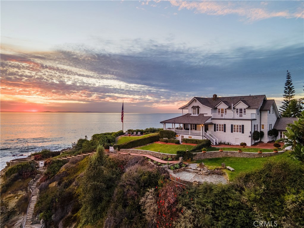 A deep connection to history, a striking setting, and the exciting possibilities of reinvention, make 139 Moss Street a truly unmatched offering in the California luxury home market. This scenic and recognizable home sits on a 1.1-acre +/- gated parcel in Laguna Beach known as Moss Point and is permeated by a sense of peace and true stillness. Ocean breezes sweep across gardens and stone paths lead to two spectacular view points, as staircases chiseled into the coastal bluff give direct access to sandy coves and a naturally-occurring pool. Crisp white siding and a covered porch create a picturesque scene where it’s easy to imagine President Woodrow Wilson lingering during his visits to this place, once under consideration to become the “Western White House”. The 4,325 +/- sq. ft. residence with 5 beds and 6 baths has been modernized, while preserving the character of its 1917 roots. Windows throughout the living areas artfully frame crystal blue skies and deeply hued sunsets, and an upgraded kitchen features granite counters and a large island for entertaining. Bedrooms are found on all three floors and offer mesmerizing views to all who visit. Bathrooms are upscale yet maintain a simplicity that honors the home’s vintage. A bonus room on the lowest level provides additional living space, with French doors that open to a patio bathed in sun and salty air. This storied property is a singular point not to be missed along the California coast.