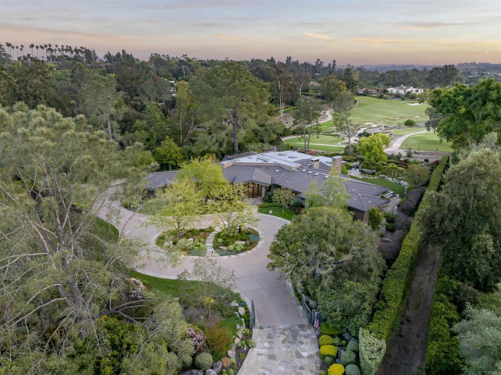 Located on the premier lot on the renowned Rancho Santa Fe Golf course...Front Row and Center…perfectly situated on 1.55 pristine acres, is one of only 41 homesites with golf course frontage. With some of the best views capturing both the 4th green and fairway and the 5th tee and fairway of this Max Behr designed golf course that originally opened in 1929, and has just completed a beautiful transformation. Style, attention to detail and masterful construction find harmony within this single-story custom designed and built estate encompassing approximately 5,545 sq feet of living space. Walls of doors open to the outdoor living/dining room, with oversized stone fireplace, al fresco kitchen, heaters, electric sunshades and is perfectly conceived for seamless indoor/outdoor living, entertaining and enjoying the spectacular and peaceful golf course and Westerly views. Beautiful hardwood floors and neutral painted walls lend warmth and texture to the interiors with an open concept floorplan. The light-filled great room with vintage lumber beams and disappearing glass doors soak up the expansive views and has custom designed and crafted shelving with built ins and a stone fireplace. The great room opens to the formal dining room with walls of windows, a service bar designed with all amenities and sitting/game area with climate-controlled wine storage. The open concept kitchen, is a chef’s fantasy with top of the line appliances, a large stone flanked center island, a breakfast bar and a light filled informal dining area overlooking the beautiful lush grounds, Koi pond and golf course. There are two offices both lined with custom shelving and cabinetry and two powder rooms. The primary suite is over sized with custom spa inspired bath detailed in stone and an oversized well designed dressing room. There are an additional two suites of bedrooms both are generous in size, one has a large sitting area and a kitchenette. In addition, there is a light filled laundry room with a wrapping/craft area and a three-car garage with golf cart storage. One can enjoy easy access to the golf course, and the equestrian/walking trail. Other amenities and features: Beautiful rose garden. Abundance of outdoor parking. Hand carved walnut front doors with art glass. Koi Pond. This home is just moments from the coveted Village in RSF for shopping and dining, Roger Rowe Schools, world renowned RSF Golf and Tennis Clubs, and within easy access to some of Southern California's best beaches and major highways. This is a once in a lifetime opportunity to own one of the best and most desirable homes in one of the best and most desirable locations on the golf course in the Covenant.