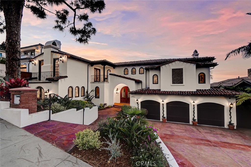 This custom home sits on a sprawling 11,999 SF lot and was meant for living on a grand scale! A dramatic entryway opens to soaring ceilings and a gently curving stairway that beckons visitors to the open, main great room that centers around a floor-to-ceiling fireplace. Imagine entertaining guests around the huge home bar area complete with ample counter space and a convenient pass-through window to the wrap-around deck. Any mixologist would be right at home with dual beverage centers, an ice maker and dishwasher drawer! The kitchen was designed to accommodate large holiday gatherings with dual sets of appliances and an extra large farmhouse sink. A center island offers great prep and presentation space while a breakfast nook sits close by. The kitchen is flanked by a large family room to one side, and a grand formal dining room to the other. A double door entry opens to the private master retreat with a massive walk-in closet. The master bath enjoys a deep, jetted soaking tub, an over-sized walk-in shower complete with a Mister Steam system and dual vanity areas topped with Kohler sinks. On the entry level, a second master suite features a jack-and-jill bath that connects to what is currently used as a den/home office. This is an excellent option for multi-generational living as this conjoining area could serve as a private living room. As a home office, the room enjoys beautiful custom library shelving and a custom in-laid tile floor design. The main bedroom level finds not only the remaining bedroom suites, but a huge media/playroom that opens wide to the private backyard. The yard is large enough to accommodate a future pool and currently “sports” a sport court area, a sun deck and a large, covered patio. A winding stairway allows direct access to the wrap-around upper deck area. Imagine entertaining all generations on all occasions - from cocktail tables to multiple bounce houses, this yard is meant for parties and gatherings of all kinds! Additional bonuses include four guest powder rooms, a huge vented storage room (possible future wine room!), a second bonus storage closet, and a side-by-side 3 car garage with a storage/workbench bay that could potentially convert to a fourth garage space. With parking for up to 6 on site, this is a home ready to receive family and guests on a regular occasion! Just minutes from Downtown and the beach. If you are seeking large scale living in a densely populated beach town, you’ve just discovered a gem!