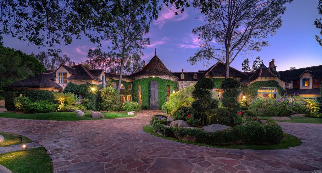 This one-of-a-kind architectural award-winning French country home is located on a beautiful 3.6 acres in the premier Rancho Santa Fe community of Fairbanks Ranch. This European-styled home was designed by architect Don Edson and just rebuilt by custom builder Todd Parnell. It has been featured as a 3-time award winner in Homes & Gardens magazine. Located on a quiet cul-de-sac, one approaches the massive rustic wooden gates that open onto a manicured flagstone circular driveway, 3.6 acres of lush landscape, and a variety of plants and trees on tiered levels with large boulders and gardens. A wishing well and bridge over the bubbling creek add serenity and charm in addition to the numerous patios for entertaining. The interior grounds greet you with a large Koi pond at the entry. A magnificent solid wood door opens to a grand foyer that includes a fireplace and formal sitting area, along with oversized French doors that reveal the rose garden and water feature just outside. 35’x50’ great room with wood beam ceiling and magnificent entertainer’s bar provide the ideal setting for any gathering. Steps away is the wine tasting area that would rival any winery with a magnificent 2nd story office on the upper level. The primary bedroom suite offers a retreat area upstairs perfect for an exercise room or secondary oversized office. Each en-suite bedroom has its own private quarters for additional privacy and peace. Resort style pool, waterfall, and 10-person jacuzzi enhance any get together. Enjoy a game of tennis or basketball on the freshly painted court and be prepared to be swept off your feet.