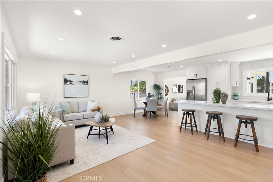 Completely remodeled to create an open floorplan design. Light and bright living room greats you as you enter. Luxury vinyl plank floors are throughout the home. The stunning kitchen highlights the space with a center island that can be used for dining or entertaining. Custom cabinets include a pantry and lazy Susan, plus soft close cabinets and drawers. Quartz counters with a herringbone marble backsplash add elegance to the space. Stainless appliances are included with a refrigerator, gas range, dishwasher and microwave. A separate laundry closet houses your stackable washer and gas dryer. The spacious dining area is accessible to the kitchen, living and family rooms. Step into the dramatic family room and enjoy the vaulted wood beam ceilings and a floor to ceiling brick fireplace with wood mantle. All the windows have been upgraded to double pane windows. Recessed lighting and lighted ceiling fans offer convenience day and night. Remodeled bathrooms have new vanities, quartz counters, custom mirrors and tiled tub surround in hall bath. The primary suite offers its own bathroom with a large custom tiled shower.  Completely re-landscaped front and rear yards with new concrete slabs, sprinklers, grass and greenery. Brand new roof too! Make this dreamy beach home yours today.