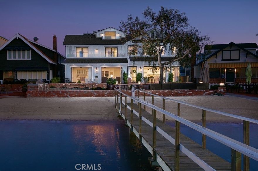 This spectacular Eastern Seaboard-style home, likely one of the most gracious and desirable bayfront homes ever to be built in Newport Harbor, is located on picturesque Buena Vista Boulevard, one of the Balboa Peninsula’s most coveted waterfront locations, a lush tree-lined walk-street commanding some of the finest views of the Newport Channel and main turning basin of the harbor, and whose owners enjoy the luxury of a privately owned sandy bay beach. Newly built in 2017, on a double lot, with 60' of frontage, the house is a compilation of the skills of architect Brad Smith, builder Ken McMillan, and Serendipite design. This timeless home will make you “swoon;” it has all the vintage style and character of a great New England beach house with walnut hardwood floors throughout, gleaming white-painted shaker cabinets, stylish stonework in seaglass hues, wood paneled walls, and an abundance of built-ins everywhere with solid Mahogany tops; in addition to its classic styling, the house was built with every amenity for modern beach living with bi-folding metal doors, stainless steel commercial grade appliances, an elevator servicing all levels of the home and an abundance of smart home features.  With spectacular views of Newport Harbor’s main turning basin, colorful sunsets, the yacht basin, and the snow covered San Bernardino Mountains, this gracious home with nearly 5,200 square feet of living space, six bedrooms and eight baths, room for everyone, and a large brick waterfront patio will entice the buyer who seeks the best of the bay and beach lifestyle. The property has two private piers, a variety of options for your boats, its proximate to the Newport Harbor Yacht Club, Balboa Library, Balboa Peninsula beaches, restaurants, and the world famous Boardwalk and Fun Zone. This home is a rare opportunity to purchase one of the Peninsula’s most coveted waterfront properties.