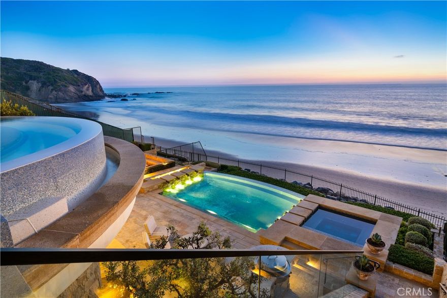 Settling for less isn’t an option at this absolutely stunning villa on the sand at The Strand at Headlands in Dana Point. Unobstructed front-row views span the azure Pacific Ocean, crashing waves, southern Orange County’s golden coastline, Catalina Island and the imposing headlands of historic Dana Point. Every level of the custom estate opens to the ocean, welcoming fresh sea breezes, natural light, and the hypnotic sounds of the surf into nearly every room. Extending approximately 10,576 square feet, the bespoke oceanfront mansion redefines elegance and sophistication with uncompromising craftsmanship and unyielding attention to detail. Heated limestone floors throughout add to the luxurious ambiance of the home. An appropriately grand entrance leads to a floating circular staircase that is crowned by a glass ceiling on the third level and provides a dramatic focal point on every floor. An elevator also serves each level of the home, which hosts five ensuite bedrooms and 7 full and 2 half baths. The formal foyer leads to a chic parlor, a formal dining room, and a massive great room with fireplace. Disappearing glass pocket doors open the great room to a large loggia that showcases a floating cantilevered spa with acrylic bottom that overlooks the beach. An island kitchen features a nook with built-in seating, and a separate catering kitchen and service bar. Take the stairs or elevator up to the top floor, where bedroom suites include a five-star owners retreat with sitting area, fireplace, ocean-view balcony, an oversized walk-in closet with island, and an exquisite bath. It’s all about fun and entertainment on the lowest floor, where a game room, billiards room, glass-enclosed wine cellar, service kitchen, fifth bedroom and a gym are located. This floor opens via a disappearing glass wall to a loggia with massive sunken wet bar. Beyond the bar awaits a resort pool and spa, a built-in island with grill, a seating area with open-air fireplace, extensive stone decking and direct beach access. Created by Homer Oatman of Oatman Architects, the estate was built by Mike Reeves of Corbin Reeves Construction and reveals exceptional interior design by Ohara Davies-Gaetano. Sequestered behind guarded gates, The Strand at Headlands is one of the most coveted oceanfront communities in California and offers more than one mile of coastline, 70 acres of parks, scenic trails, a beach club and easy access to resorts, shops, restaurants and outstanding schools.