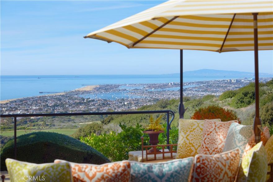 Ever-changing by day and night, the phenomenal panoramic views of 'Villa Saffron' are in a league of their own. They are experienced from both levels of the St. Tropez-inspired villa at guard-gated Pelican Crest in Newport Coast. The immersive vistas stretch across lush fairways, a canyon, the azure waters of the Pacific Ocean, Newport Harbor, San Clemente and Santa Catalina Island. Enchanting city lights reach as far as Palos Verdes. The terraced grounds tower 604 feet above sea level. They command front-row views that complement a backyard with upper and lower terraces, four lawn areas, loggias, custom fireplace/wood-burning pizza oven. The outdoor kitchen features a built-in 48" Lynx BBQ. Located close to the end of a private cul-de-sac, the villa showcases exquisite landscaping, a walled and gated front yard with a limestone colonnade pool, and a large, fireplace-warmed atrium. Spanning nearly 26,092 SF, the estate’s sumptuous homesite by EBTA architects, built by PrideMark, compliments an opulent interior that extends approximately 8,176 SF. It features four en suite bedrooms (one at entry-- currently used as an office), four full baths, and two half baths. An inviting foyer and grand staircase provides an elegant introduction to living areas including a media room, sunny office with enchanting views, a circular formal dining room surrounded by columns, and a spacious great room with an ornate hand-carved limestone fireplace. The chef’s kitchen boasts an oversized island, ocean-view breakfast room, butler’s pantry, two sinks, stone countertops, custom cabinetry, built-in side by side Sub-Zero refrigerator/freezer, steam oven, six-burner Wolf range, and double ovens. Note worthy materials include stone imported from France and Italy, antique French pavers, French white oak flooring, along with custom-made steel windows and French doors. All rooms except the media room offer access to an outdoor patio, terrace, loggia, or Juliet balcony, with the ocean-view primary suite boasting two decks, pocket doors at its entrance, a sitting room, two walk-in closets with custom built-ins, retractable sun shade, and luxe bath featuring a soaking tub and separate shower. Additional highlights include a 350+ bottle temperature-controlled wine cellar, wet bar, EV charging, full house water filtration and soft water by Water Techniques, Sonos sound system, Lutron lighting, as well as the option to build an ADU on the terraced lot with a spectacular view.